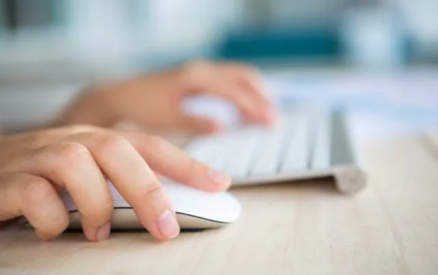Руки во время управления компьютерной мышью и клавиатурой