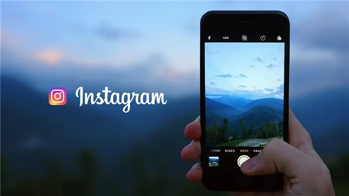 Надпись Instagram и смартфон с приложением в руке на фоне горных пейзажей